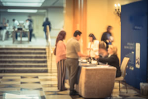 Photo of conference attendees checking in at a desk in front of the meeting area